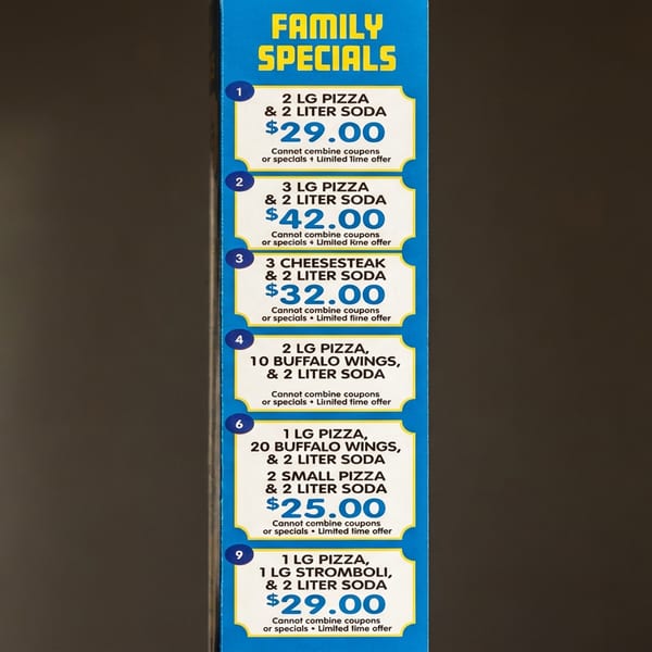 Restaurant menu displays family specials featuring pizzas, cheesesteaks, buffalo wings, stromboli, and sodas with prices.